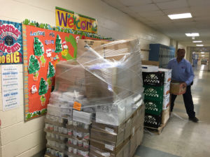 boxes of food wrapped in plastic, on a pallet, in a school hallway