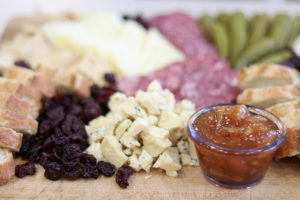 raisins, blue cheese crumbles, and a cup of marmalade on a cheese board