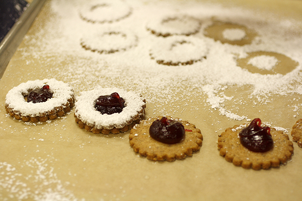 linzer cookies, so are finished and some are missing their tops still, they are on a tray with powdered sugar