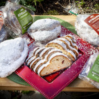 plate with stollen breads on it; one is sliced; bags with stollen surround it