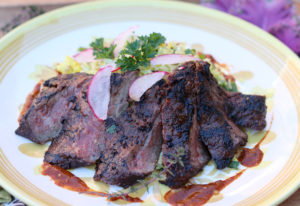 pieces of steak arranged decoratively on plate with parsley sprig and radish slices