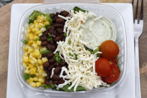 salad with corn kernels, black beans, shredded cheese, and small tomatoes on top