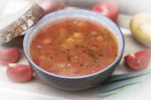bowl of vegetable soup with bread and vegetables