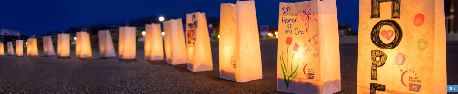 a row of luminaria (lit up paper bags) decorated by children