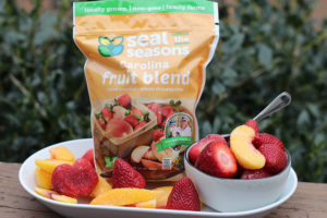bag of frozen Seal the Seasons peaches and strawberries, with fruit on a plate as well