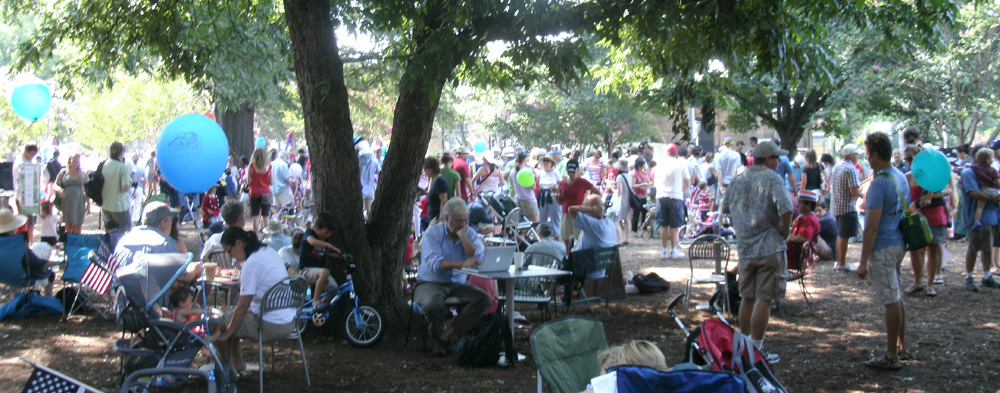 people on the lawn in Carrboro with trees and bicycles and flags