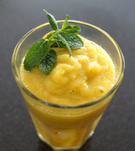 a mango-colored smoothie with mint leaves on top