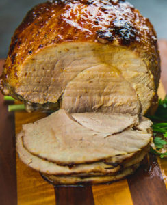 glazed ham with slices cut, on cutting board