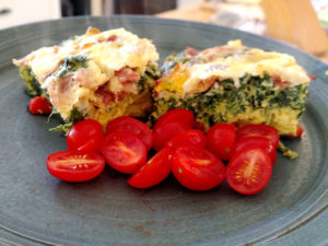 two hunks of egg casserole on a plate with cherry tomatoes
