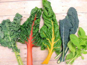 Five green leaves of different types of kale, chard, arugula