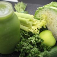 green smoothie and many green vegetables: cabbage, celery, kale, apples
