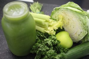 green smoothie and many green vegetables: cabbage, celery, kale, apples