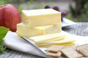 slabs of cheddar as well as slices, on plate with grapes and apple slices and crackers