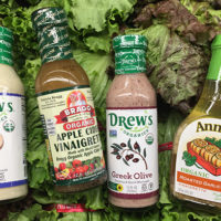 four bottles of salad dressing lying atop heads of lettuce