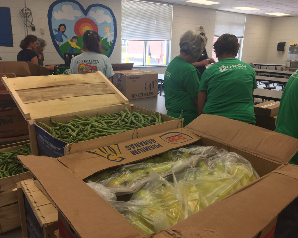 people in a school classroom unload vegetables fro boxes