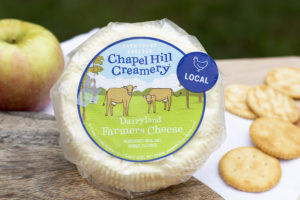 wheel of cheese in wrapper with apple and crackers