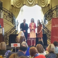 Brenda accepts award on grand staircase with Triangle Business Journal representatives