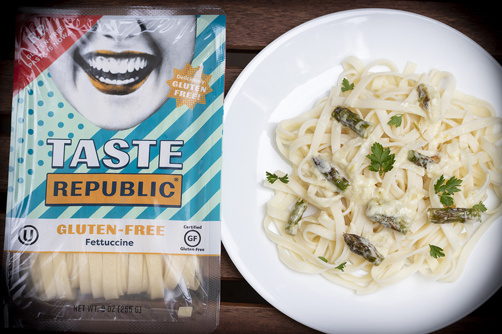 plate of noodles with sprigs of green and creamy sauce, with box of taste Republic gluten free noodles beside it