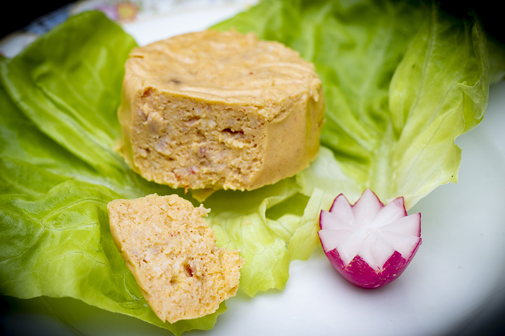 patty of cooked egg on a bed of lettuce with a decorative radish