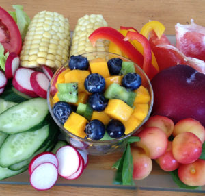 a display of fruit and vegetables including corn, blueberries, and cherries