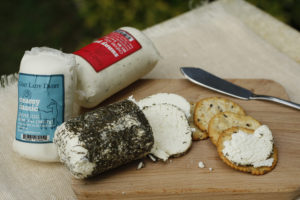tubes of cheese with one opened and cut, and spread on crackers