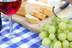 Close up of a picnic spread with grapes, cheese and wine