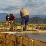 men working atop wall with mountain backdrop