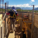 men working atop brick wall with rebar sticking up