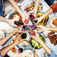Aerial view of people toasting together, over table of food