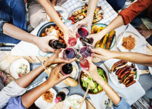 Aerial view of people toasting together, over table of food