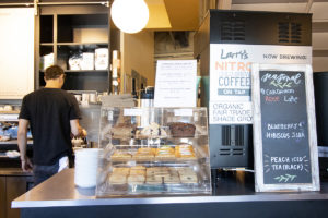 pastries in case and back of coffeemaker in restaurant, and man behind counter