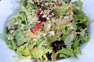 lettuce with quinoa and bits of roasted vegetables on top, and goat cheese
