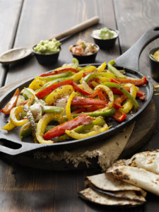 cast iron pan with sauteed slices of peppers, as if for fajitas