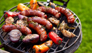 Grilled sausages and vegetables on a grilled plate, outdoors