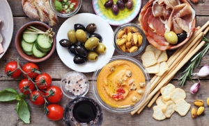 Mediterranean appetizers table concept. Dinner table with tapas selection: cured meat and salami, gazpacho soup, jamon, olives, cheese, hummus and vegetables. Overhead view.