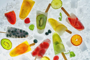 frozen pops made with clear juice containing fruit, on a bad of ice with fruit pieces