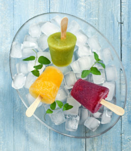 three small frozen pops with wooden sticks in a bowl of ice