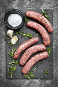 Raw sausages on slate, with herbs and spices. Overhead view.