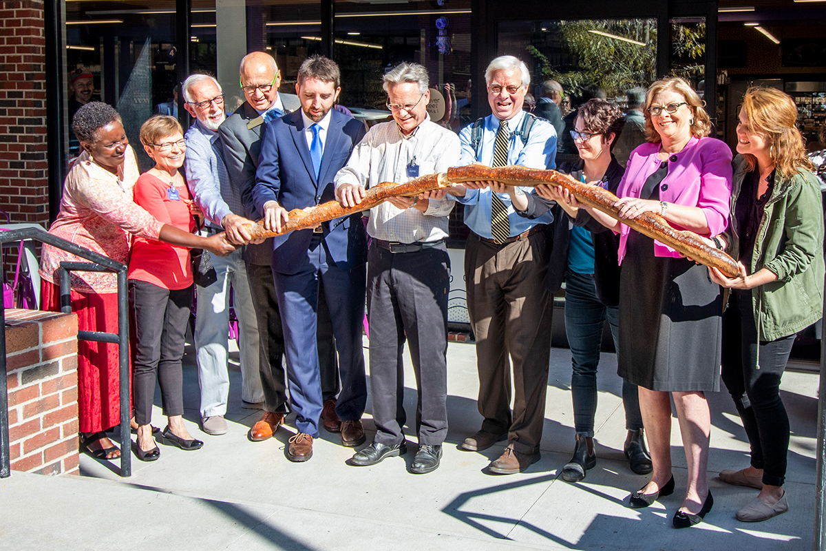 dignitaries holding six-foot baguette in front of Weaver Street Raleigh location