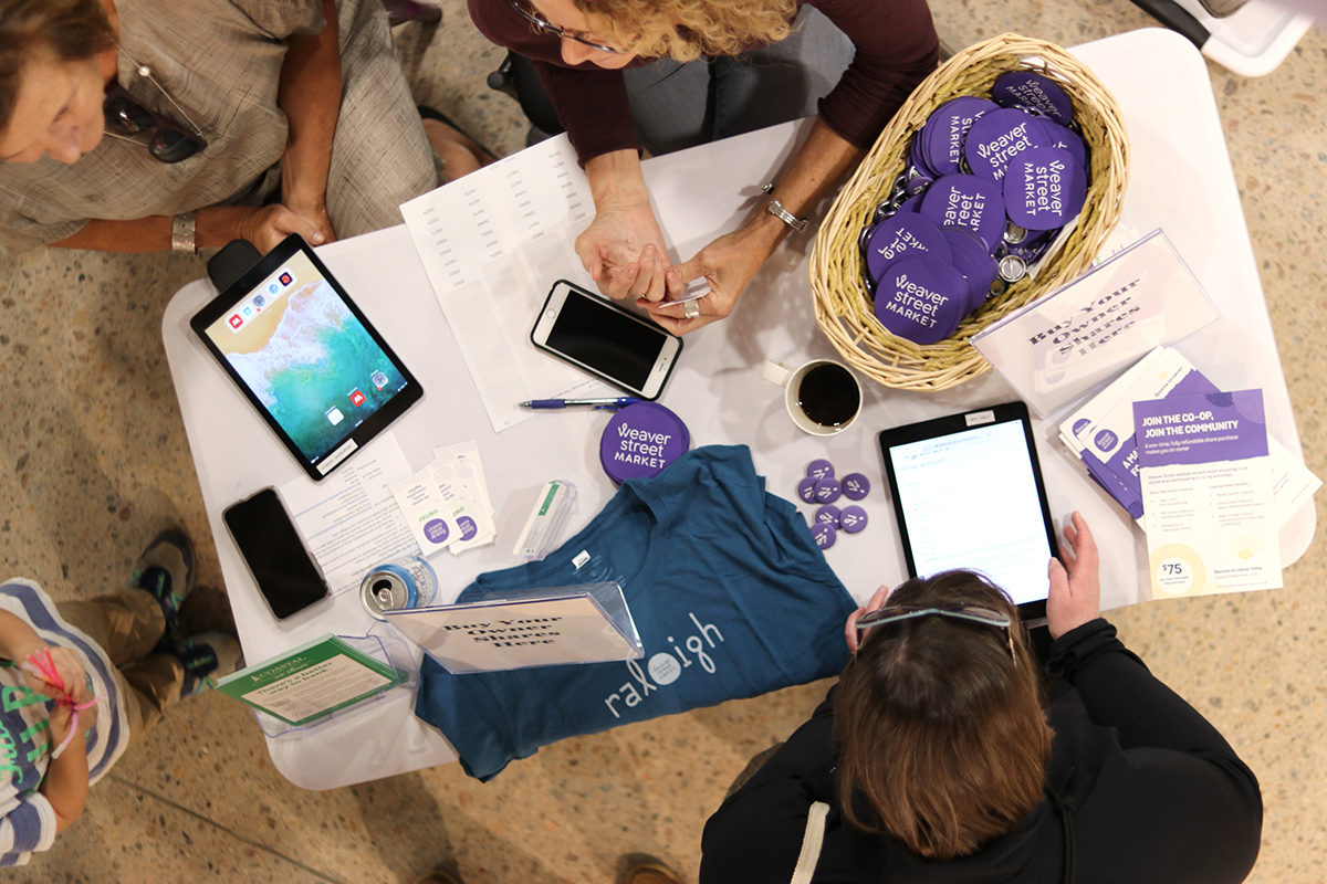 aerial view of table with tablets and merchandise like logo magnets, with person sitting at it