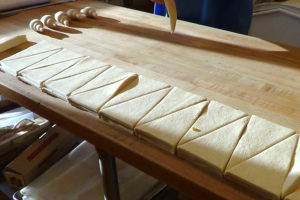 croissant dough on table being cut into triangles